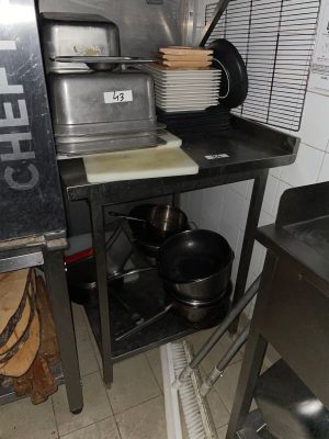 pots and pans are stacked on a metal shelf in a kitchen
