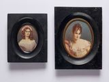 deux portraits miniatures de femmes dans des cadres noirs, posés sur une surface blanche