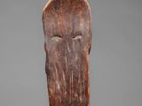 an old wooden carving of a face on a gray background