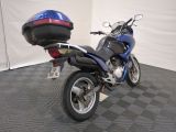 a blue motorcycle parked in a room with a helmet on the back of it