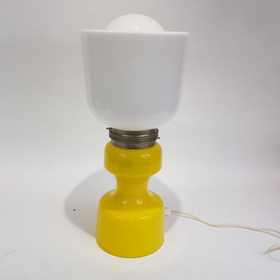 une image représentant une lampe jaune et blanche posée sur une surface blanche