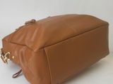 the brown leather bag is sitting on a white surface