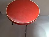 a small table with a red top sitting on a white floor