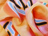 close up of a pink and yellow silk scarf with a black and white design