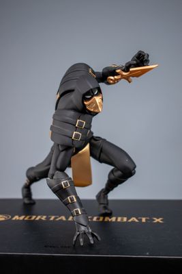 La figurine est posée sur un socle noir rehaussé de touches dorées.