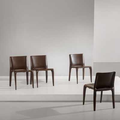 Trois fauteuils en cuir marron sont disposés sur une estrade blanche dans une pièce blanche