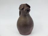 a brown vase with a dog on it on a white surface