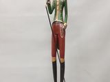figurine représentant un homme vêtu d'une veste verte et d'un pantalon rouge, tenant une canne