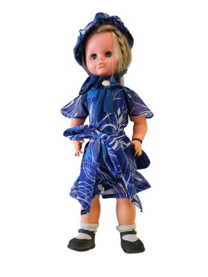 doll in blue dress and hat with blue scarf and black shoes