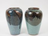 deux vases posés l'un à côté de l'autre sur une surface blanche