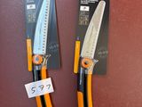 une paire de ciseaux orange et noirs posés sur une surface rouge