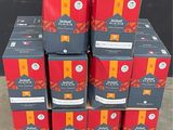 Plusieurs caisses de bière sont empilées sur une palette devant un mur noir.