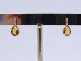pair of yellow sapphire and diamond earrings on a silver stand