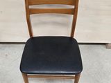 a wooden chair with a black seat and seat pad