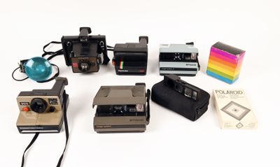 a lot of polaroid cameras sitting on a white surface