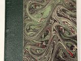 un vieux livre à la couverture verte posé sur une table blanche