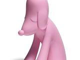 une figurine de chien rose posée sur une surface blanche