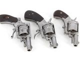 three old revolvers are lined up on a white surface