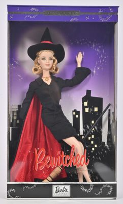 La poupée Barbie porte un costume de sorcière et une cape rouge.