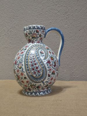 un vase muni d'une anse bleue posé sur une table