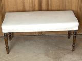 a white bench sitting in front of a wooden wall