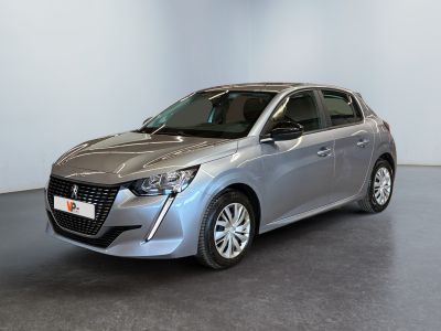 La voiture argentée est garée dans une grande pièce au sol noir.