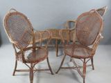 trois chaises en osier et une table sur laquelle est posé un oiseau