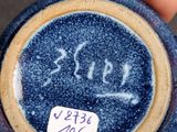 a small blue vase with writing on it in a person ' s hand