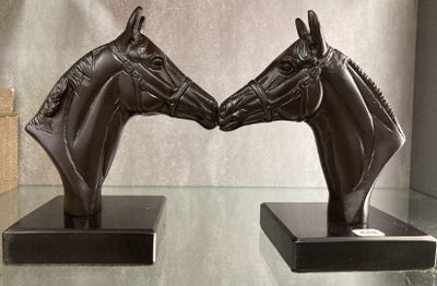 deux statues représentant deux chevaux se faisant face, posées sur une table en verre