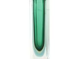 un vase vert posé sur une surface blanche