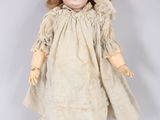 an antique doll with a white dress and brown hair