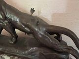 a bronze statue of a cat and a bird on a table