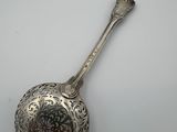 an antique silver spoon with a floral design on it