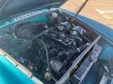 a blue car with its hood open and the engine in the trunk