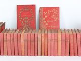 several old books are stacked on a shelf on a white surface