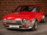 a red car that is parked in front of a brick wall