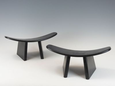 une paire de bancs en bois noirs posés sur une surface blanche