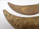 pair of antique brass spoons with engraved labels on them on a white surface