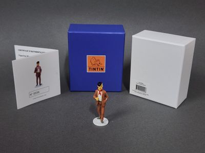 une figurine représentant un homme en costume-cravate à côté d'une boîte
