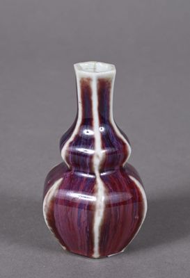 a purple and white vase sitting on a gray surface