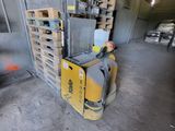 a forklift in a warehouse with pallets in the background