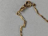 a close up of a gold bracelet with a chain on a white surface