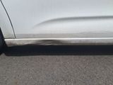 the side of a white car with a flat tire on the road