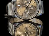 two watches sitting side by side on a reflective surface