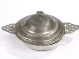 une casserole en argent avec un couvercle, posée sur une surface blanche
