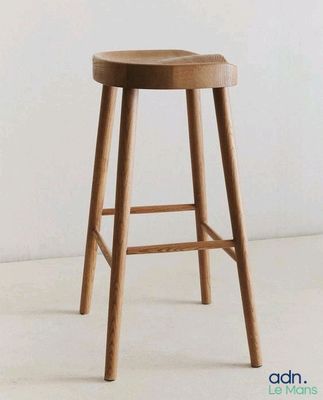 un tabouret en bois avec une assise en bois posé sur un sol blanc