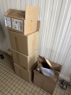 une pile de cartons posée par terre à côté d'une poubelle