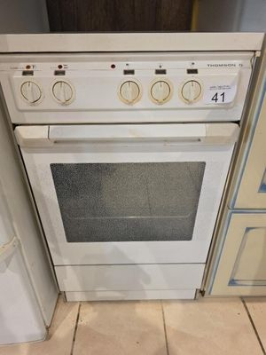 une cuisinière et un four dans une cuisine avec un carrelage au sol et des placards blancs