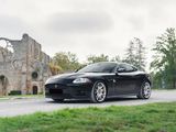 a black sports car driving down the road in front of an old building