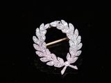 a close up of a brooch with a leaf design on it